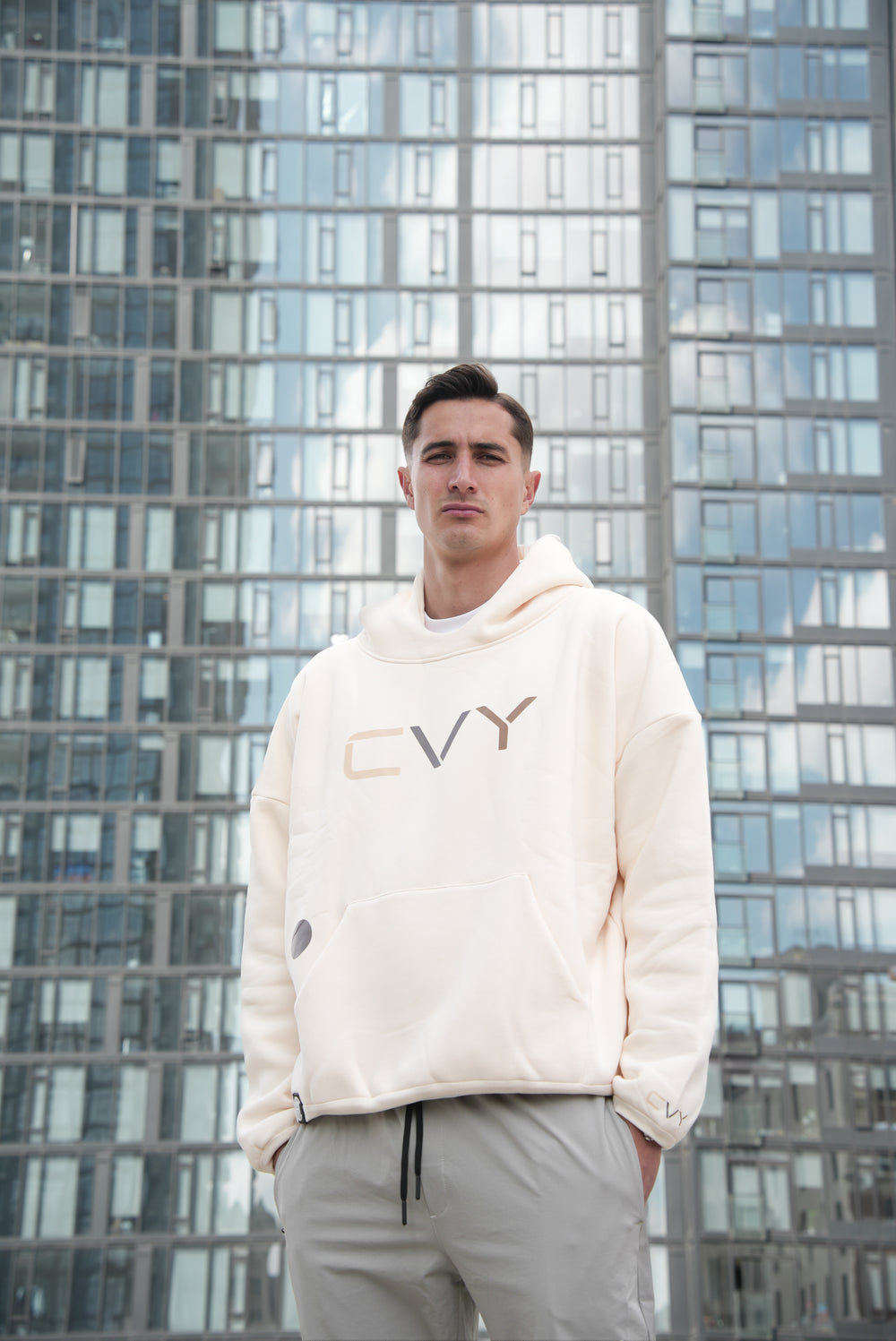Man in a CVY hoodie in front of a glass tower