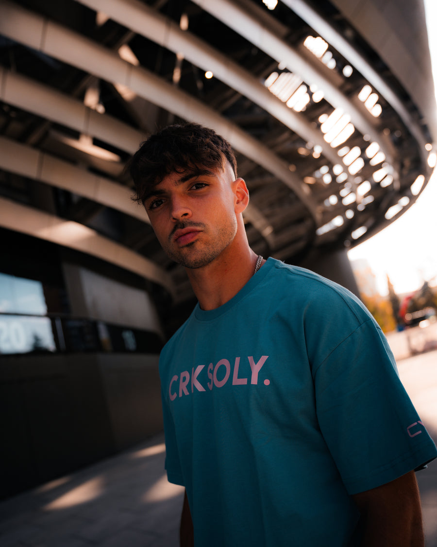 CVY athlete in a teal CRKSOLY. tee under a stadium canopy